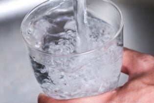 Yuto Omura holding a glass under a running stream of water.