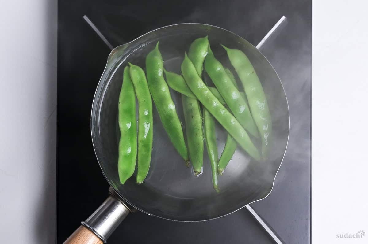blanching green beans in a pot of water on the stove top