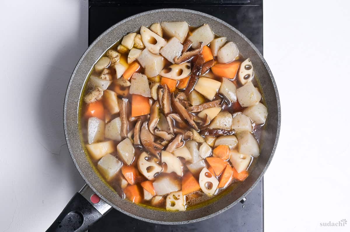 chikuzenni simmering with shiitake mushroom strips in a wide pan on the stove top