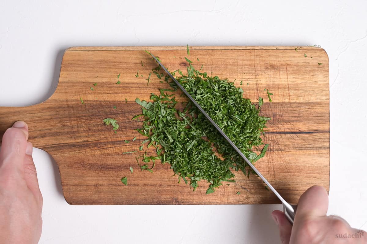 finely chopping shiso leaves (perilla) on a wooden cutting board