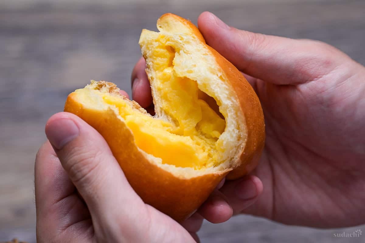 Homemade cream pan (Japanese sweet custard bun) torn in half to reveal pastry cream filling