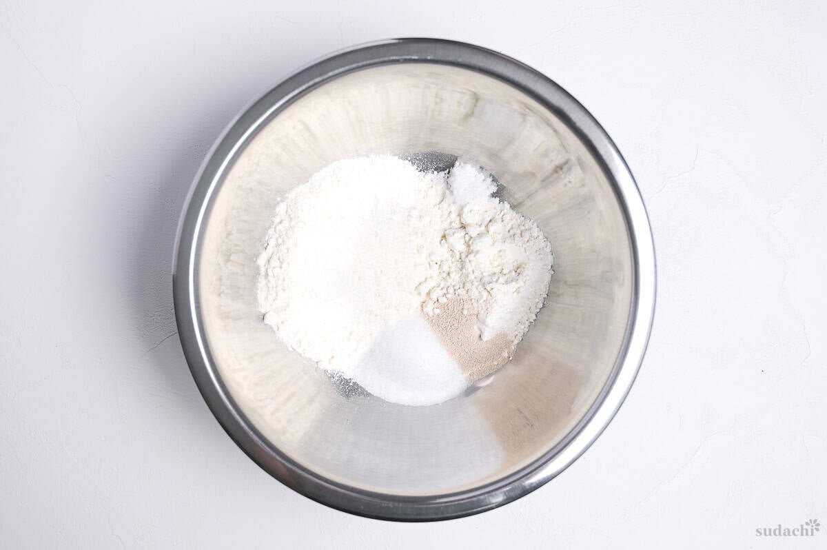 dry ingredients for Japanese sweet buns in a steel mixing bowl (flour, sugar, salt, yeast)