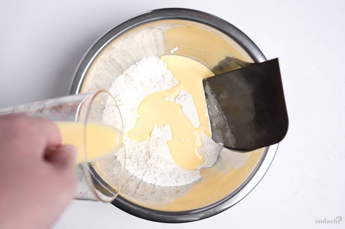pouring wet ingredients into dry ingredients to make enriched dough for cream pan