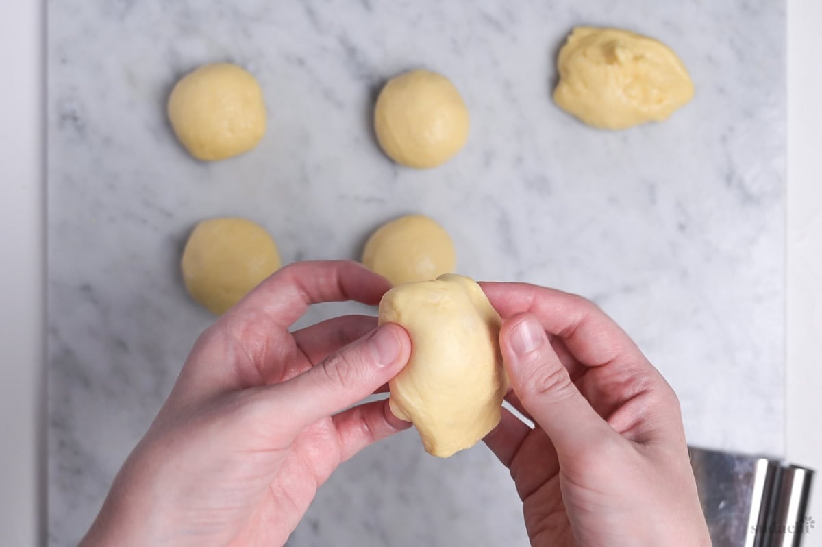 dough divided into 6 pieces, shaping by pulling edges under