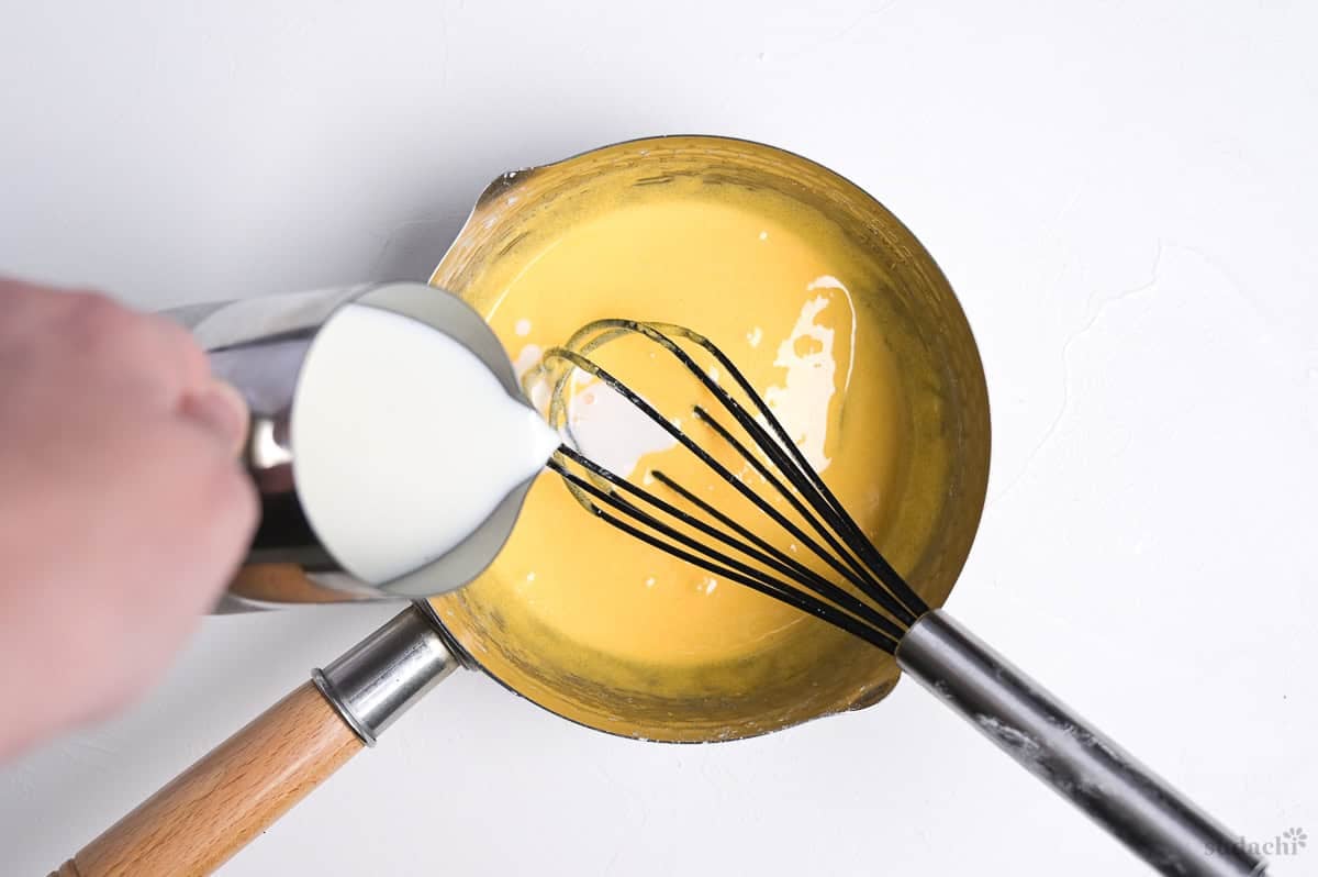 pouring milk into egg, sugar and starch mixture in a saucepan for pastry cream filling
