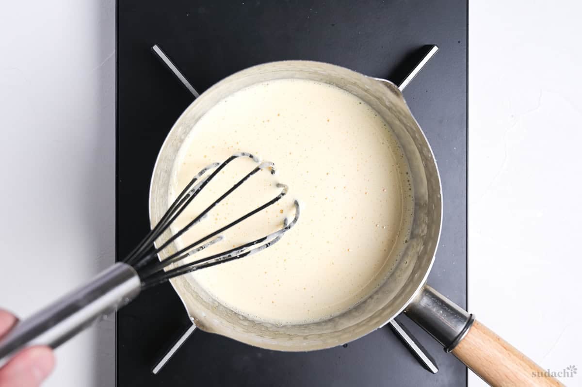whisking pastry cream in a saucepan on the stove top