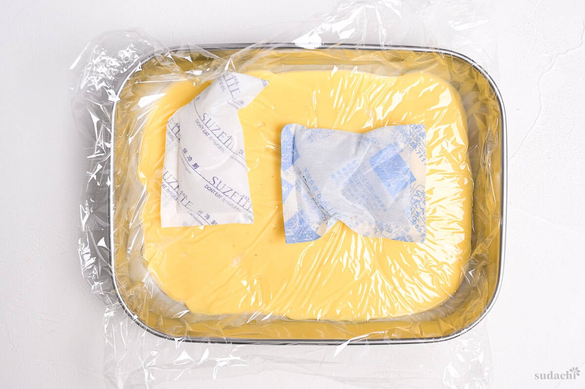 pastry cream in a steel container with plastic wrap and ice packs on top