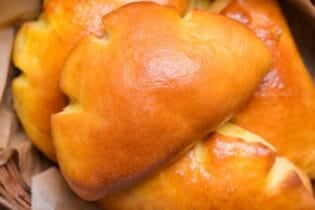 Homemade cream pan (Japanese sweet custard buns) in a wooden basket lined with baking paper close up
