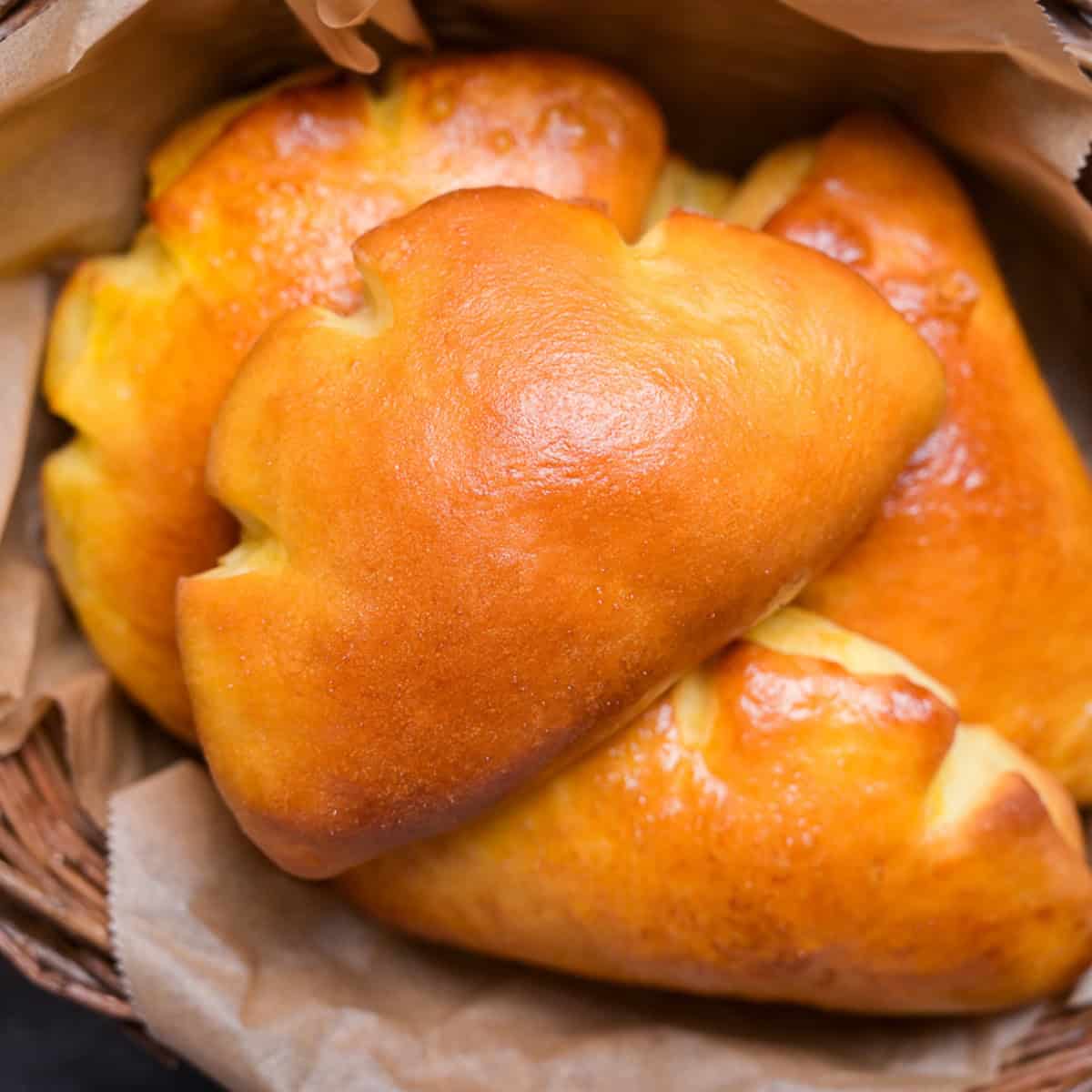 Homemade cream pan (Japanese sweet custard buns) in a wooden basket lined with baking paper close up