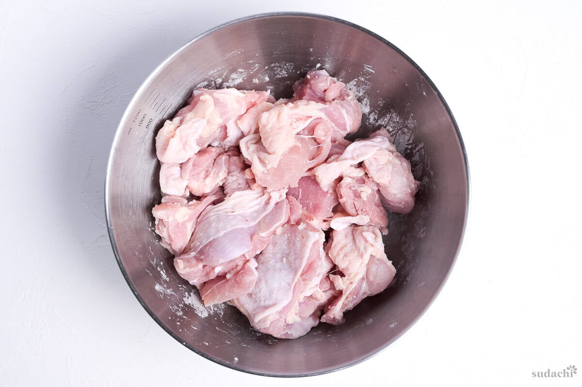 chicken thigh pieces in a bowl coated with a thin layer of starch