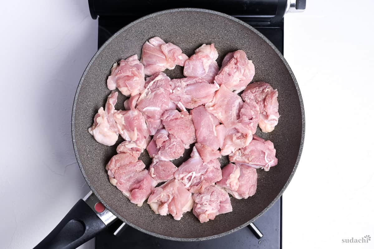 frying chicken thigh pieces in a single layer in a frying pan, skin side down, to make garlic teriyaki chicken donburi