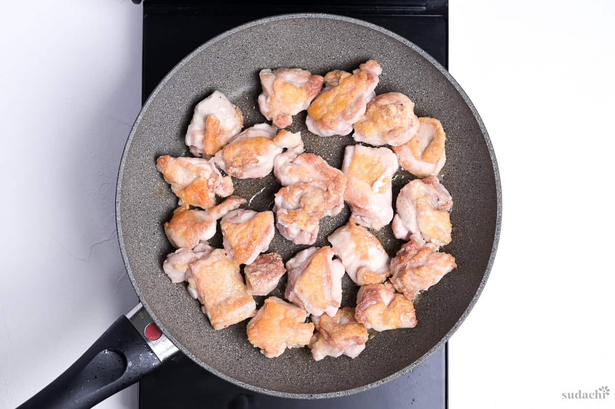 seared chicken thigh pieces in a pan on the stove top