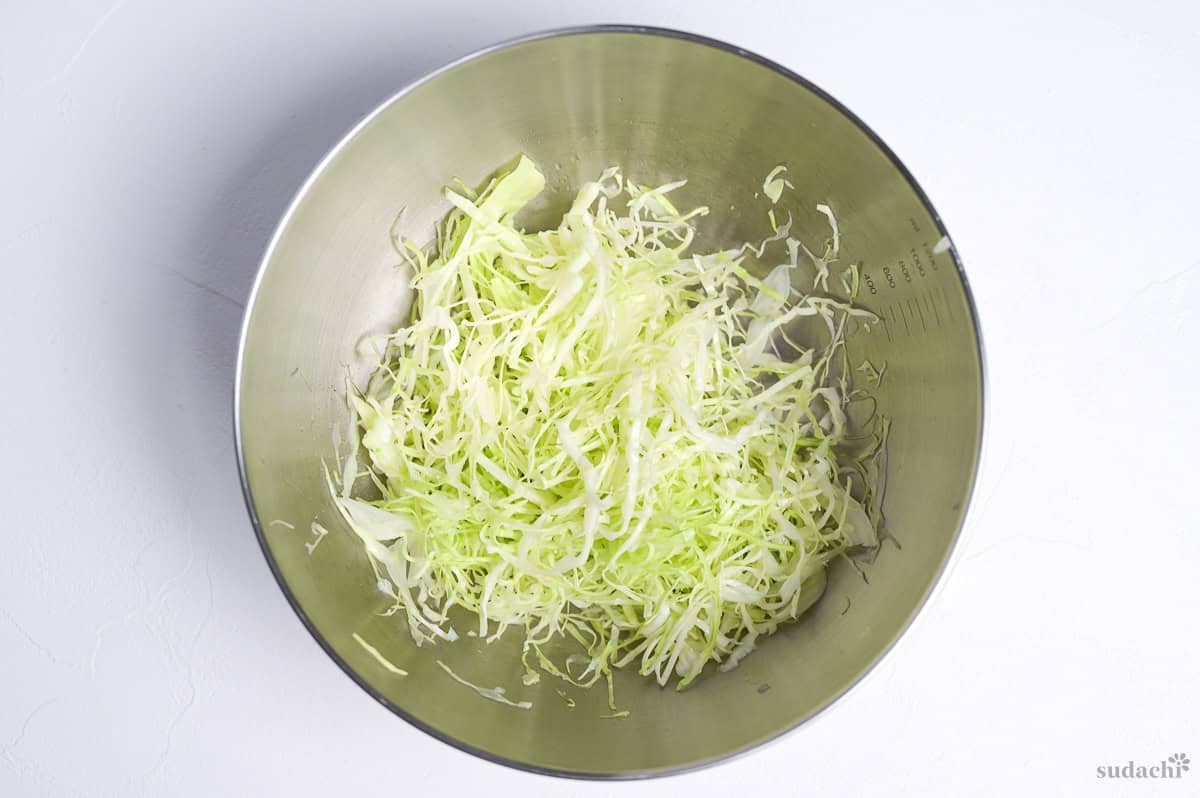 shredded green cabbage in a steel mixing bowl