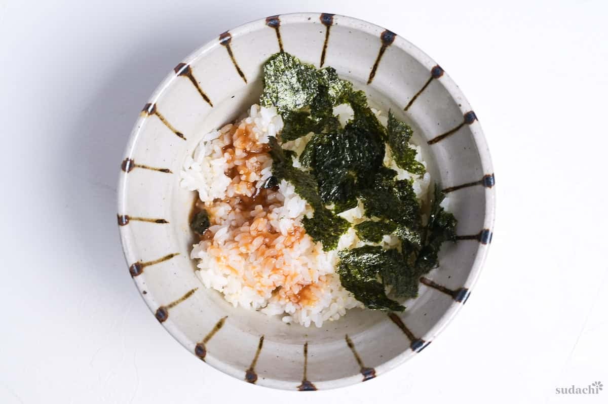 Cooked rice in a bowl drizzled with teriyaki sauce and topped with roughly torn nori