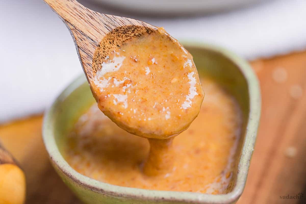 Scooping homemade Japanese goma sesame dressing onto a wooden spoon
