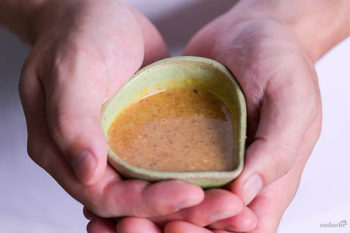 Yuto Omura holding up homemade Japanese goma sesame dressing in a small green jug