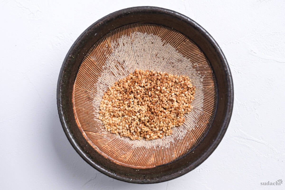 toasted white sesame seeds in a Japanese style mortar ready for grinding