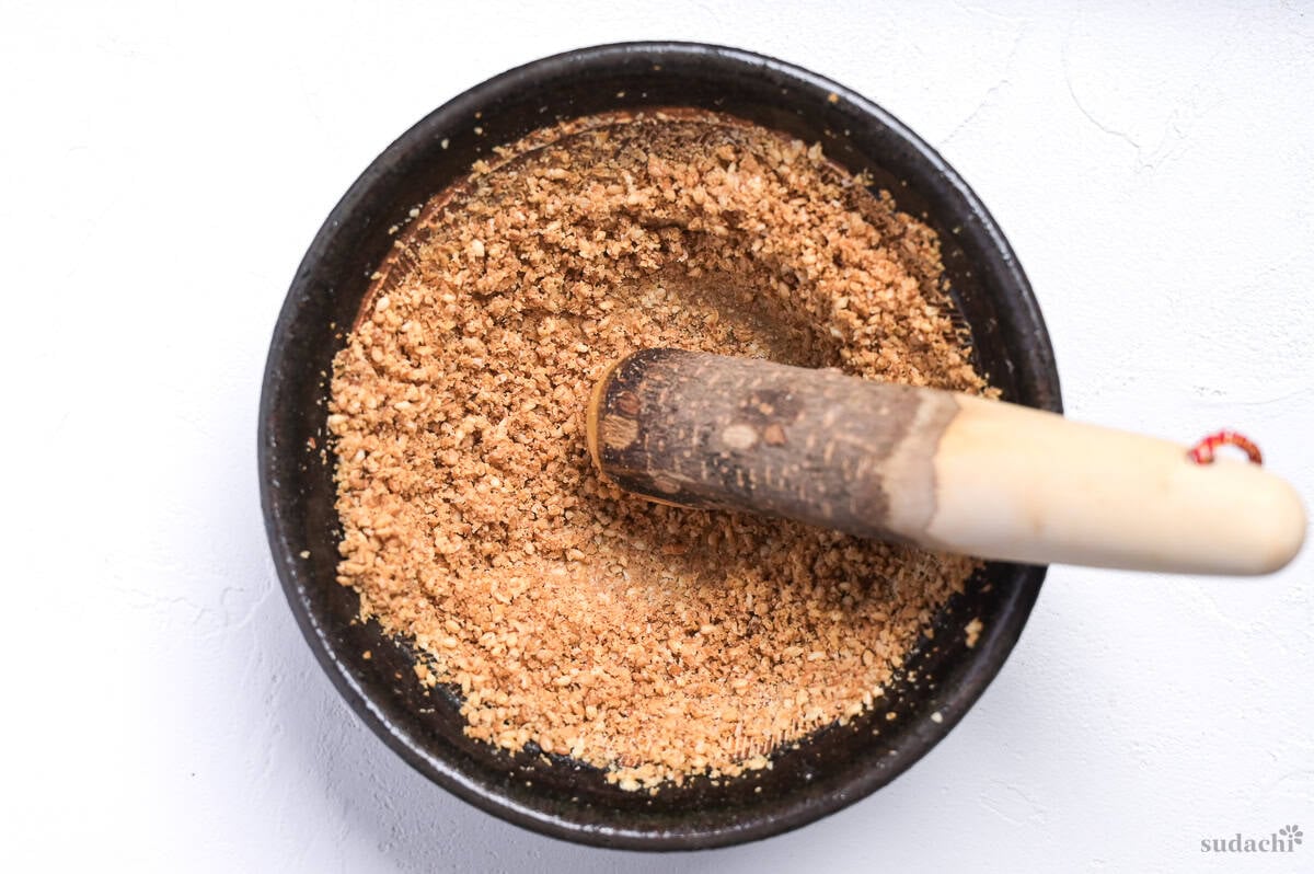 Ground toasted white sesame seeds in a mortar with rustic pestle inside
