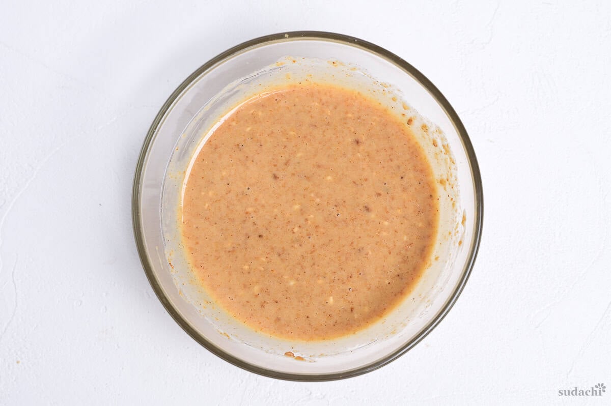 Homemade goma dressing in a glass bowl on a white background