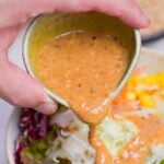 Pouring homemade Japanese goma sesame dressing over salad.