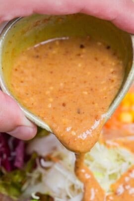 Pouring homemade Japanese goma sesame dressing over salad.