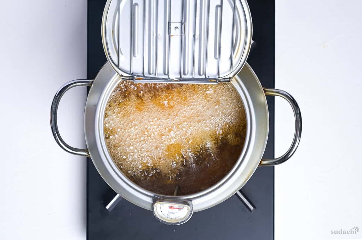 gyukatsu frying in oil in a Japanese tempura pot with thermometer