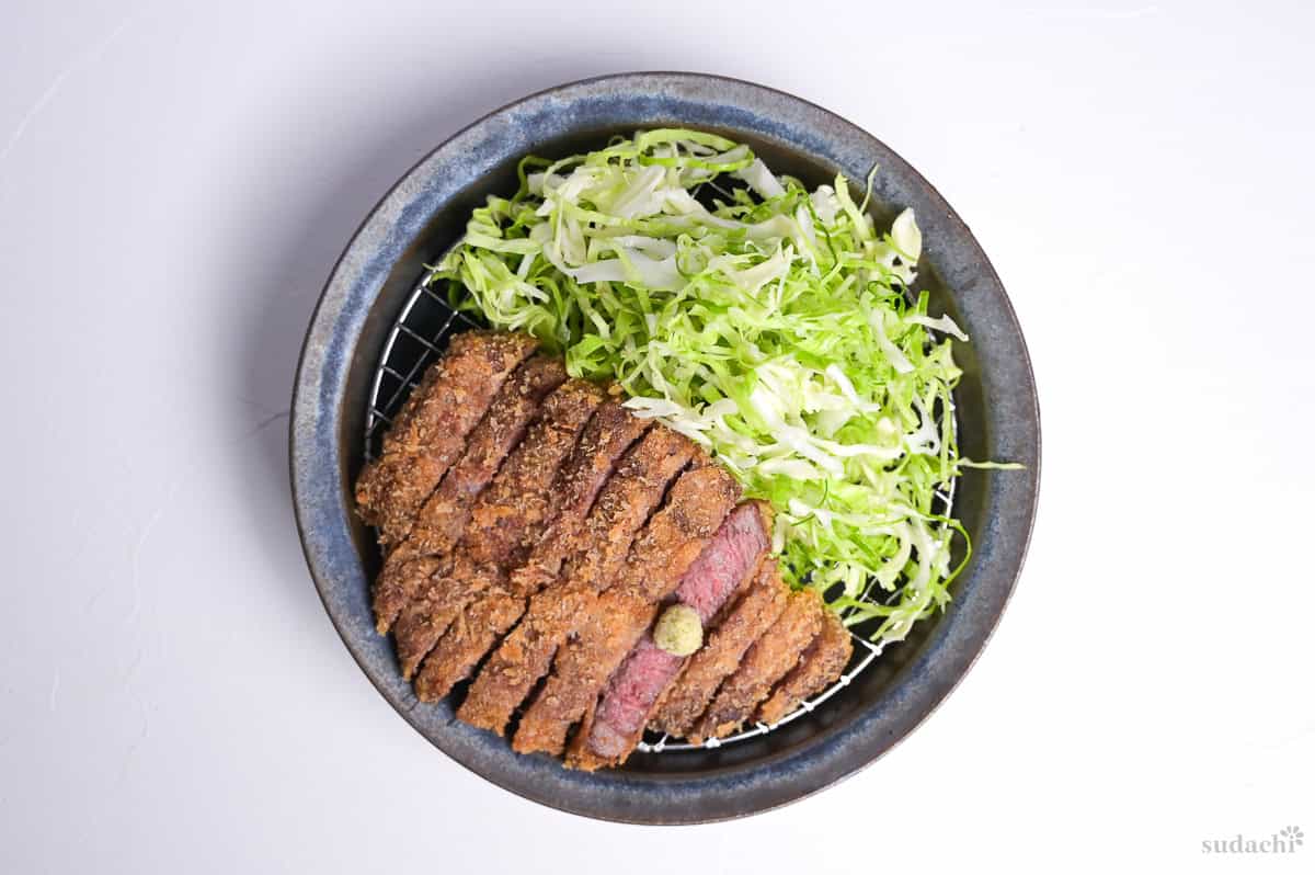 Gyukatsu (Japanese beef cutlet) cooked rare and served on a wire rack with shredded cabbage and wasabi