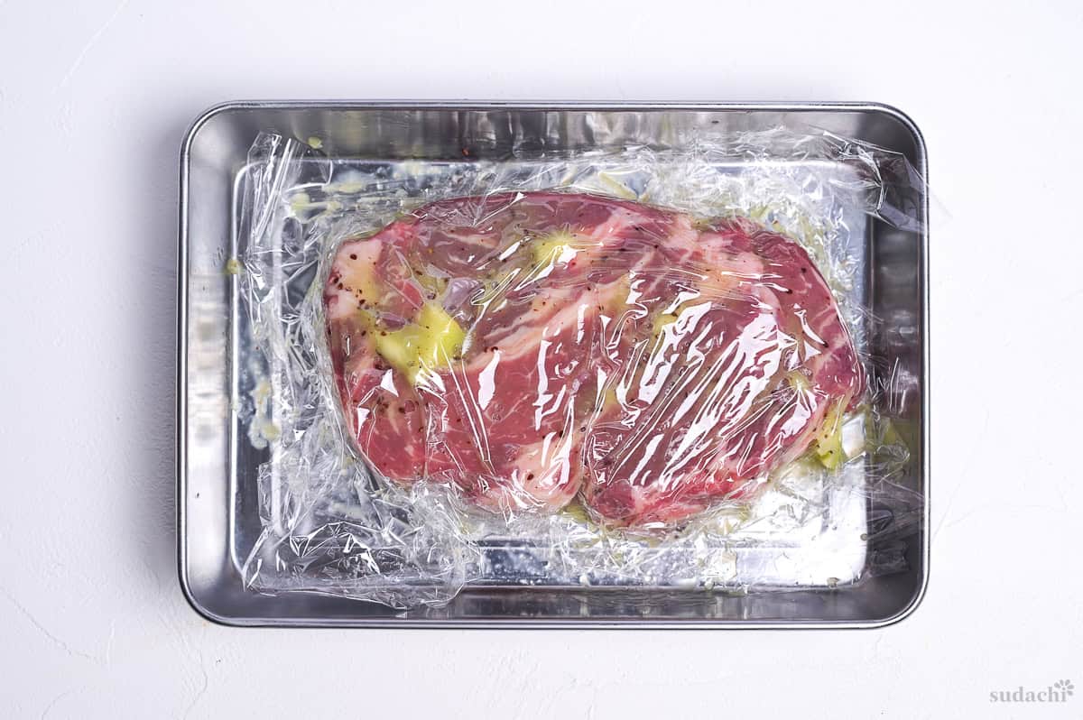 beef steak coated with kiwi and wrapped in plastic in a steel container