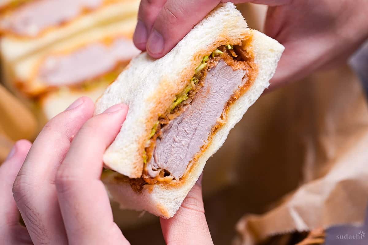 A hand holding up a katsu sando (Japanese pork cutlet sandwich)