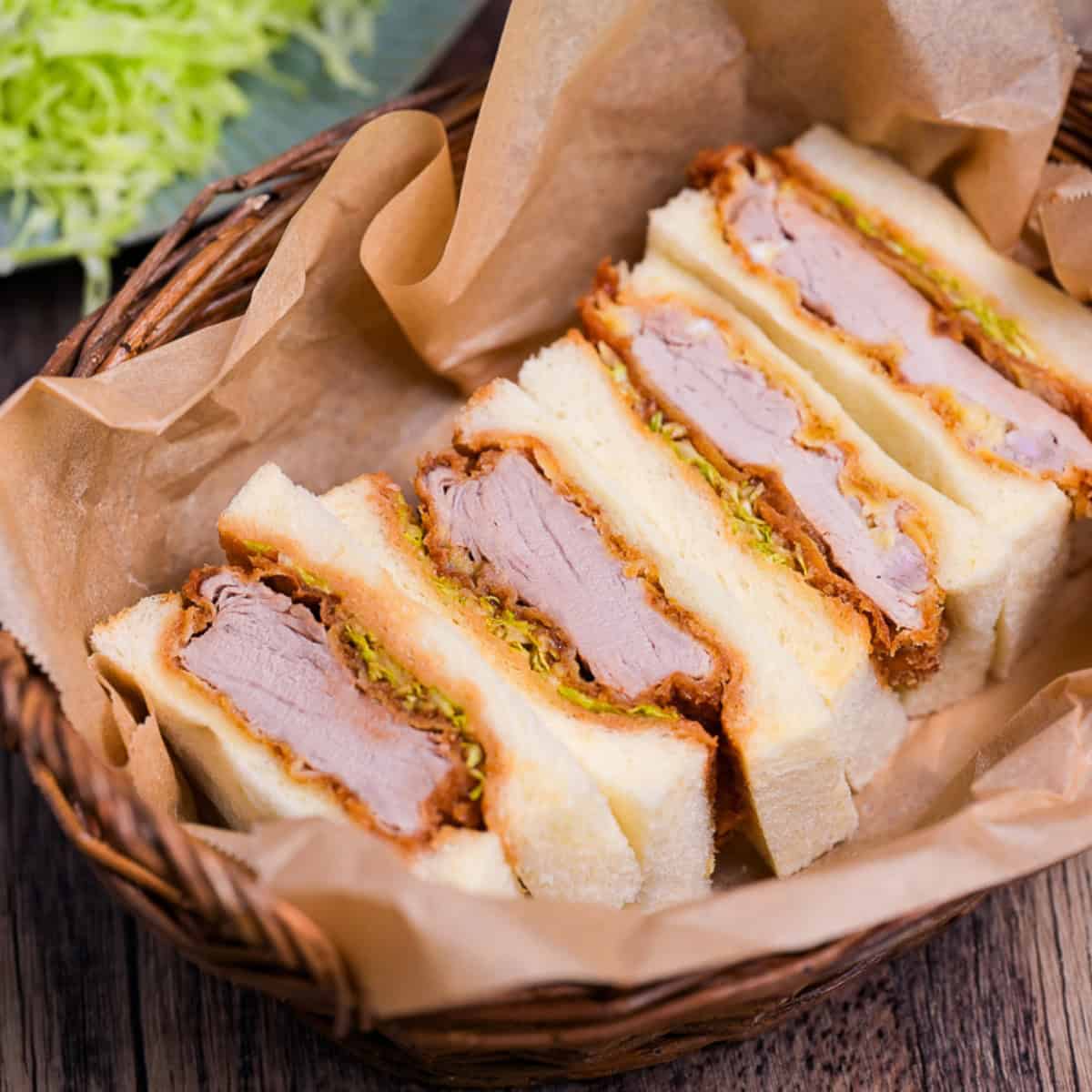 Four katsu sando in a basket lined with parchment paper