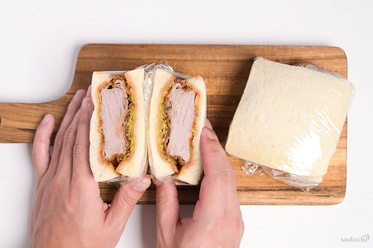 A katsu sando (Japanese pork cutlet sandwich) cut in half on a wooden cutting board