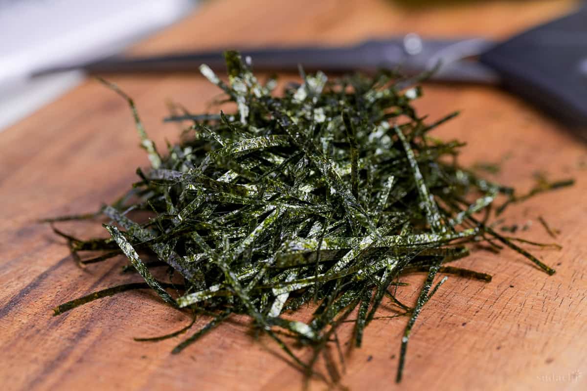 hand cut kizami nori on a wooden cutting board with a pair of scissors in the background