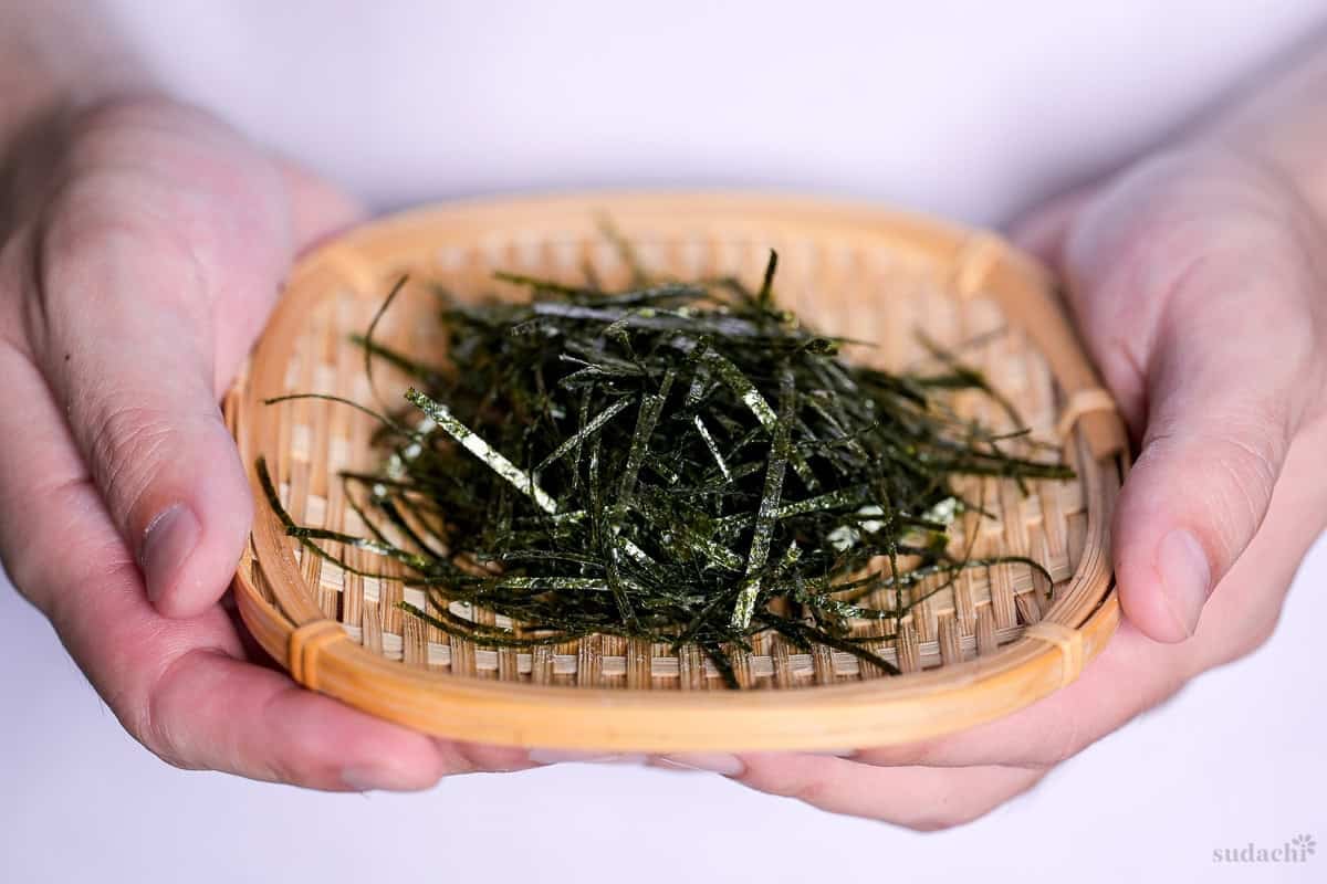Yuto Omura holding homemade hand-cut kizami nori on a small woven bamboo tray