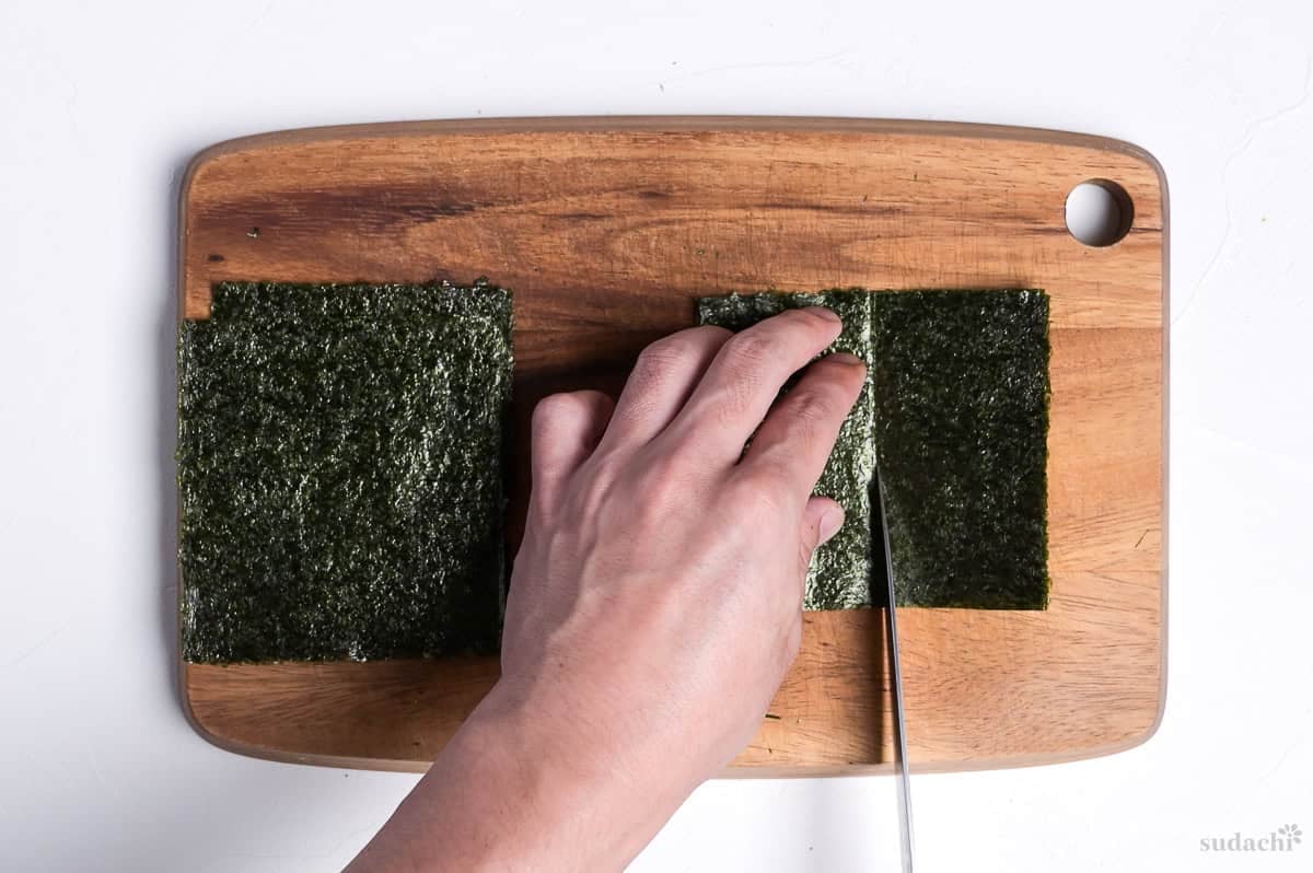 cutting nori into 8 pieces on a wooden cutting board to make kizami nori
