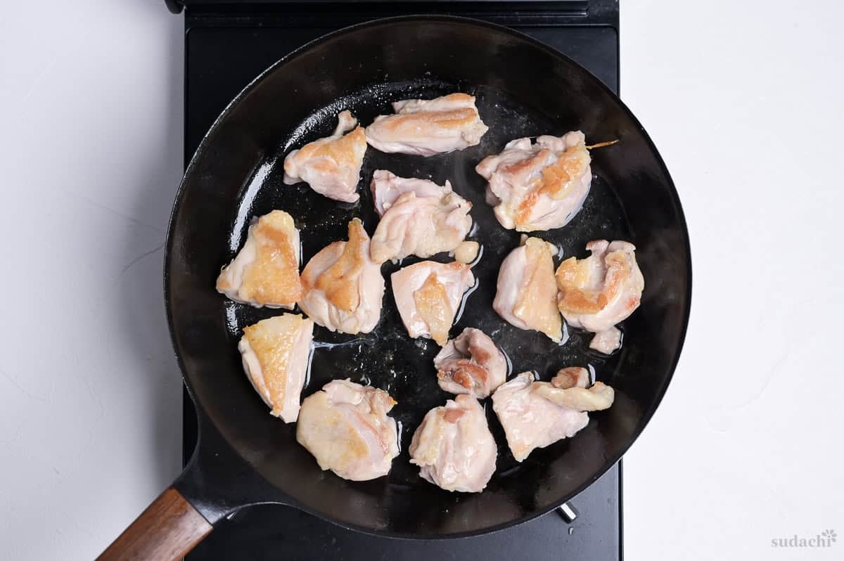 seared chicken thigh in a frying pan on the stove top