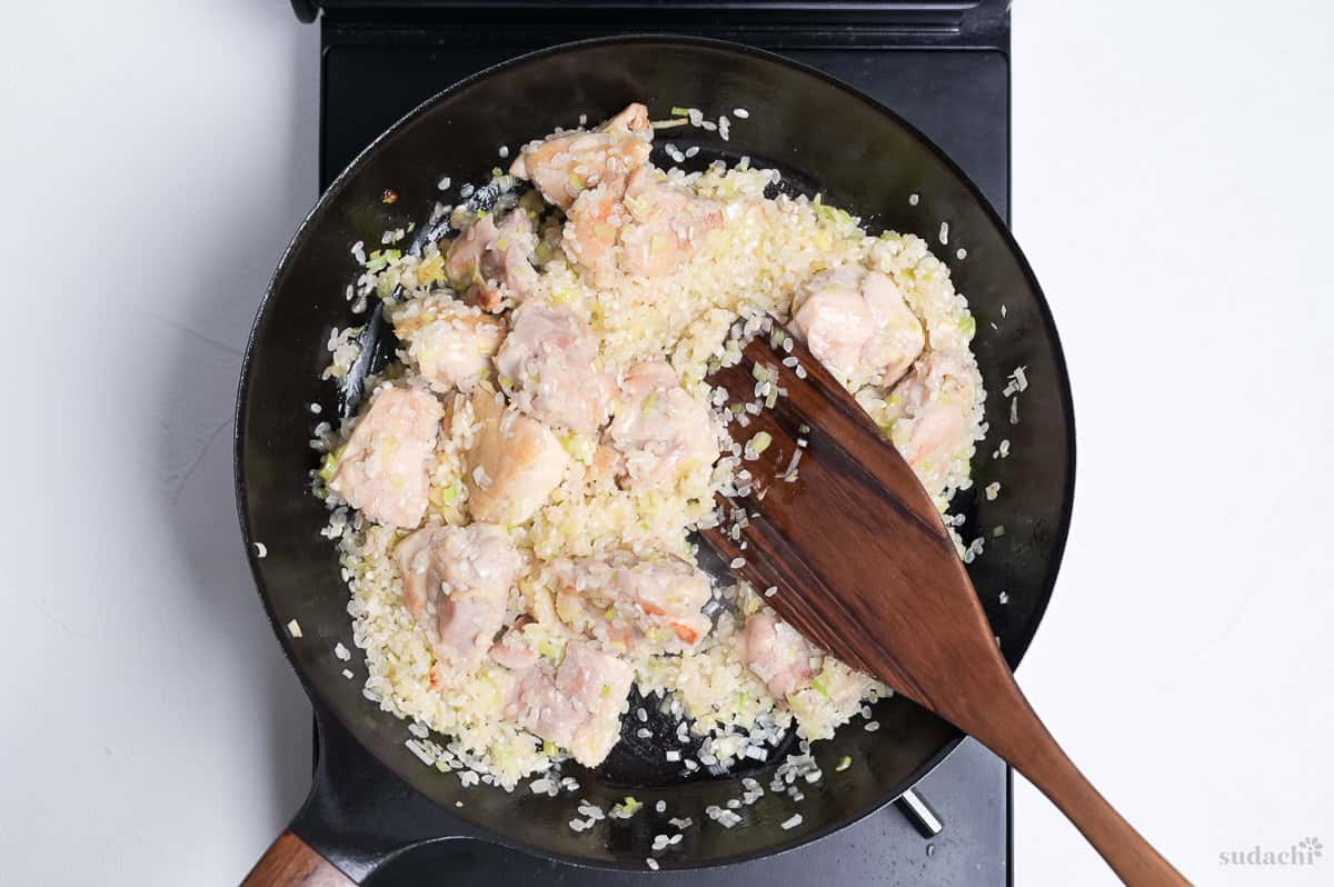 softened Japanese leek and garlic in a frying pan with seared chicken thigh pieces