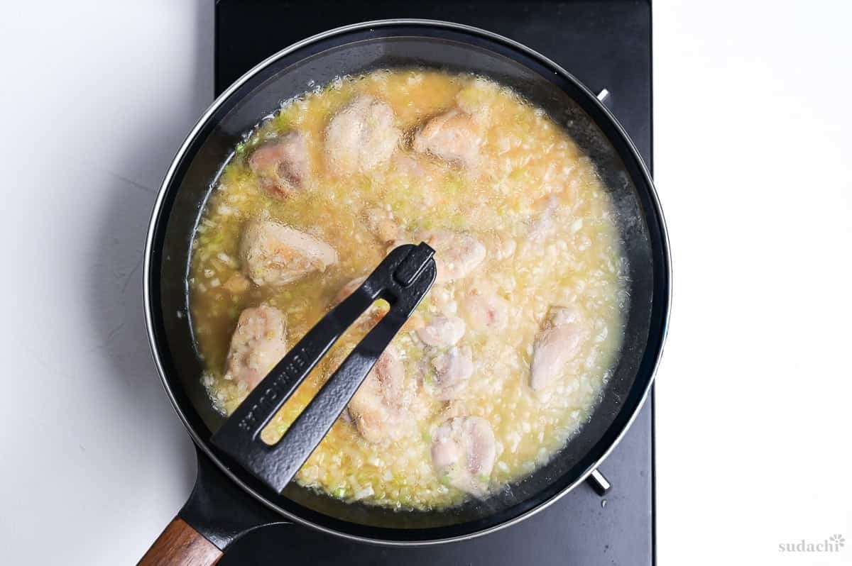 negi shio paella simmering in a pan on the stove top, covered with a lid
