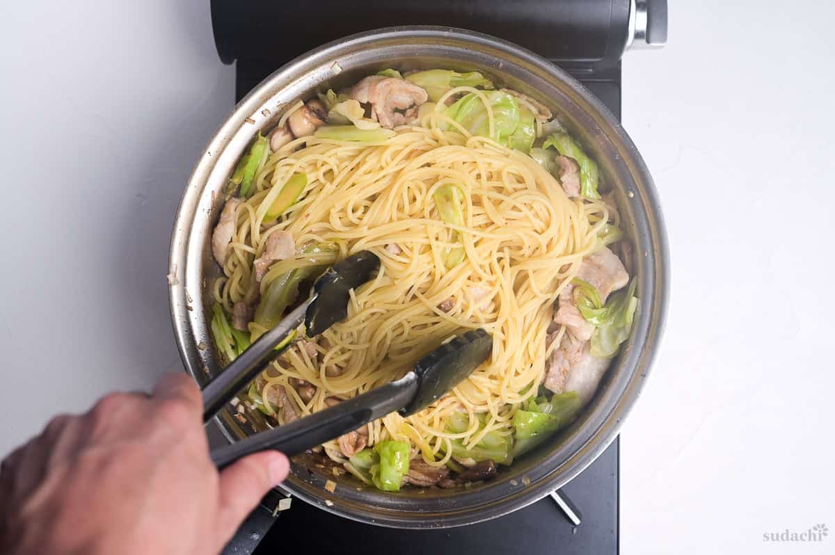 cooked spaghetti added to frying pan to make negishio spaghetti