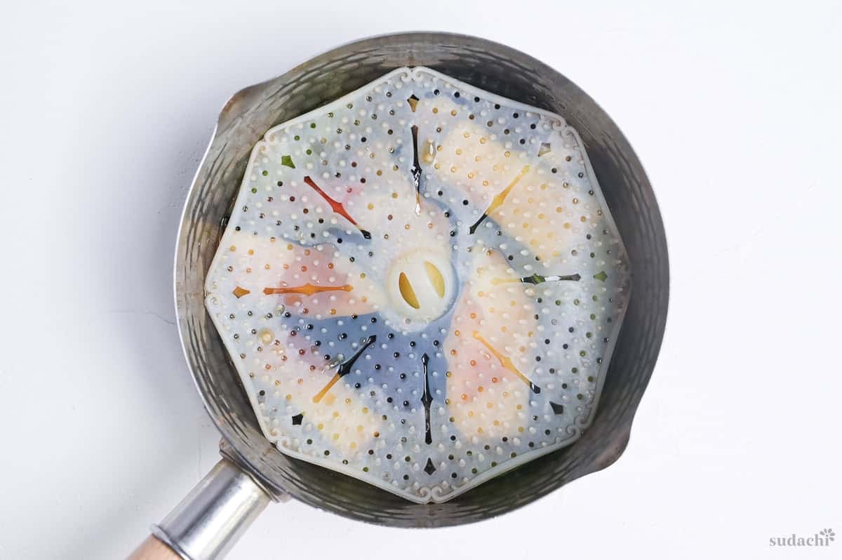 agebitashi in a saucepan with silicone drop lid weighing the ingredients down into the broth