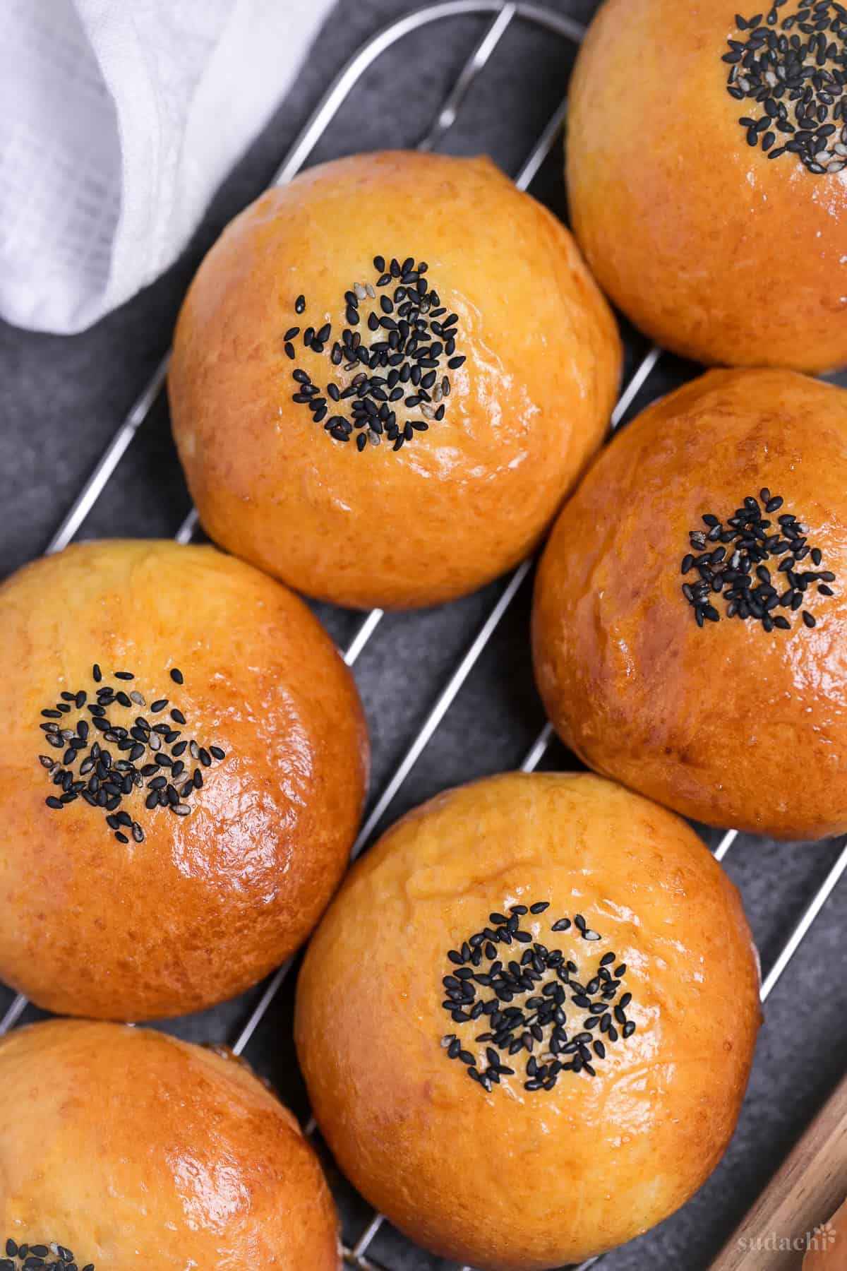 Six homemade anpan (Japanese red bean buns) stacked on a wire rack