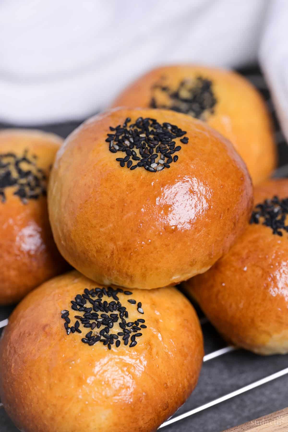 Five homemade anpan (Japanese red bean buns) stacked on a wire rack