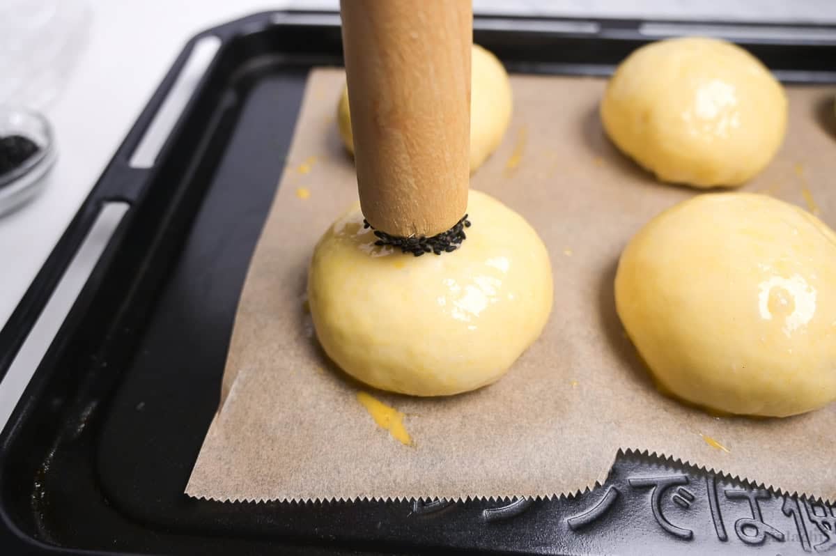 printing a circle of black sesame seeds on the top of anpan before baking
