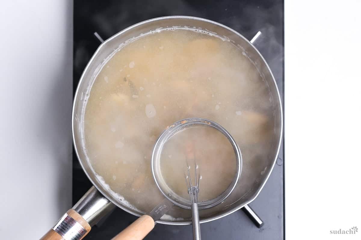 adding miso using a mesh miso strainer to asari miso soup in a saucepan