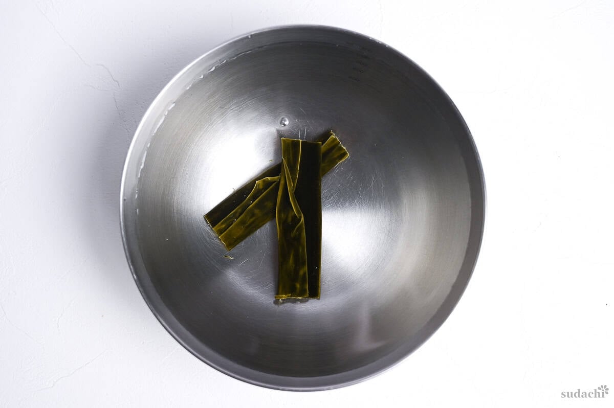 two pieces of dried kelp (kombu) soaking in water to make kombu dashi for asari miso soup