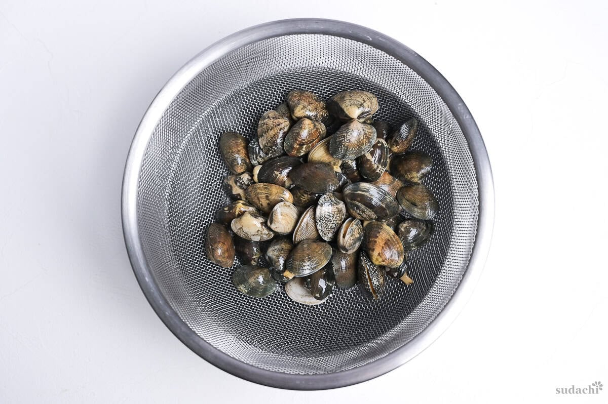 washed manila clams in a sieve over a mixing bowl