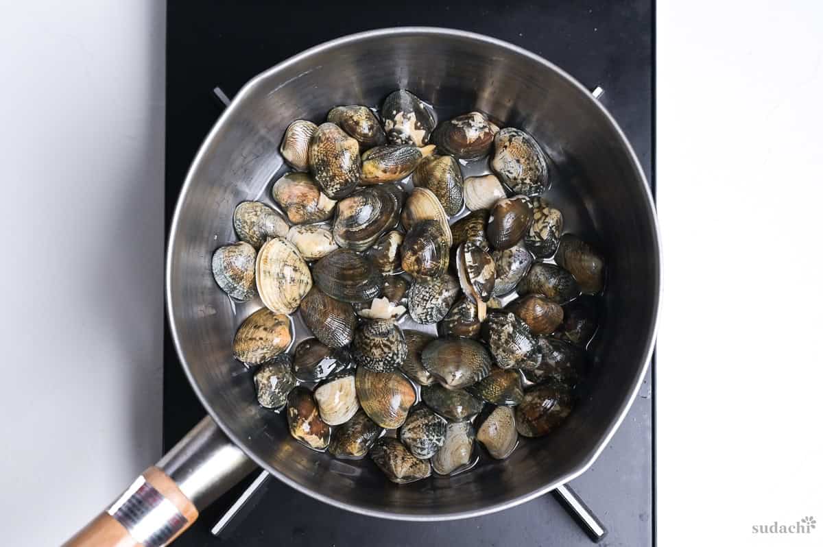 manila clams with sake in a saucepan on the stove top