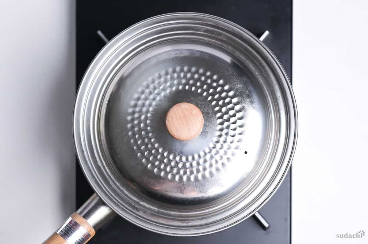 steaming manila clams in a pot with a lid