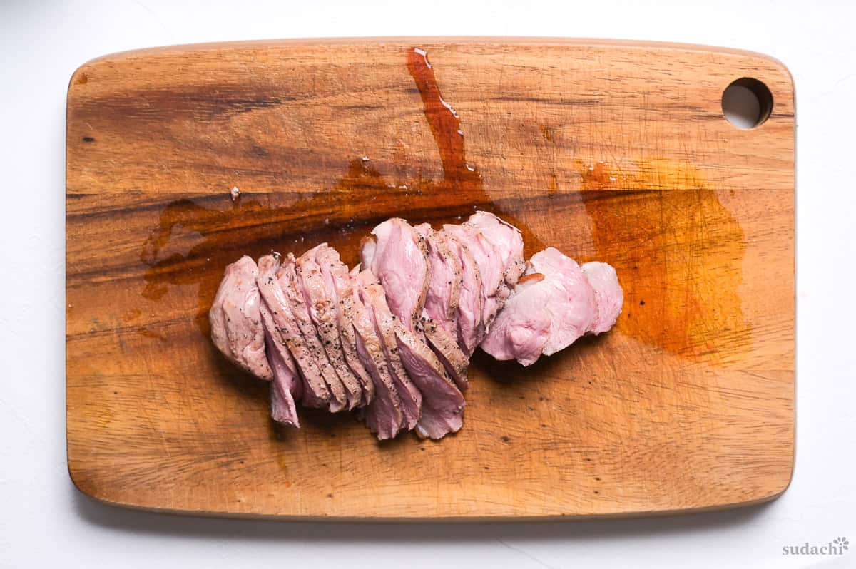 Pan-fried duck breast cooked medium placed on a wooden cutting board cut into slices