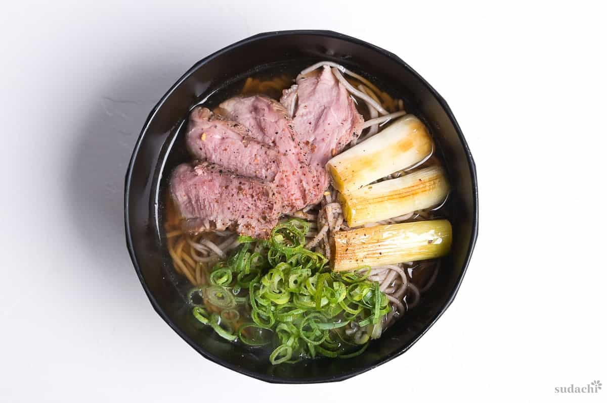 Kamo Nanban Soba in a black bowl on a white background