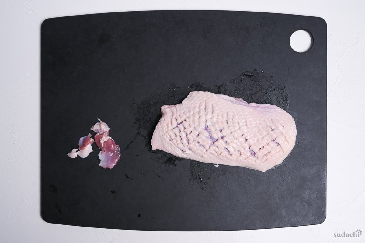 duck breast with scored fat on a black cutting board